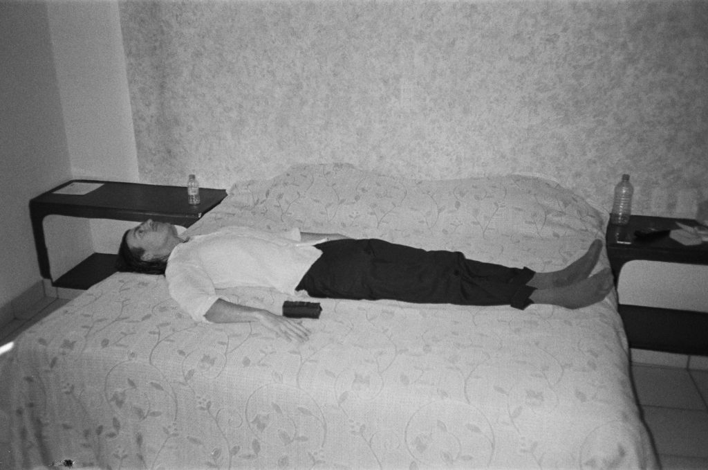 thomas bush lying on a well made bed in a manner perpendicular to the bed's own intention